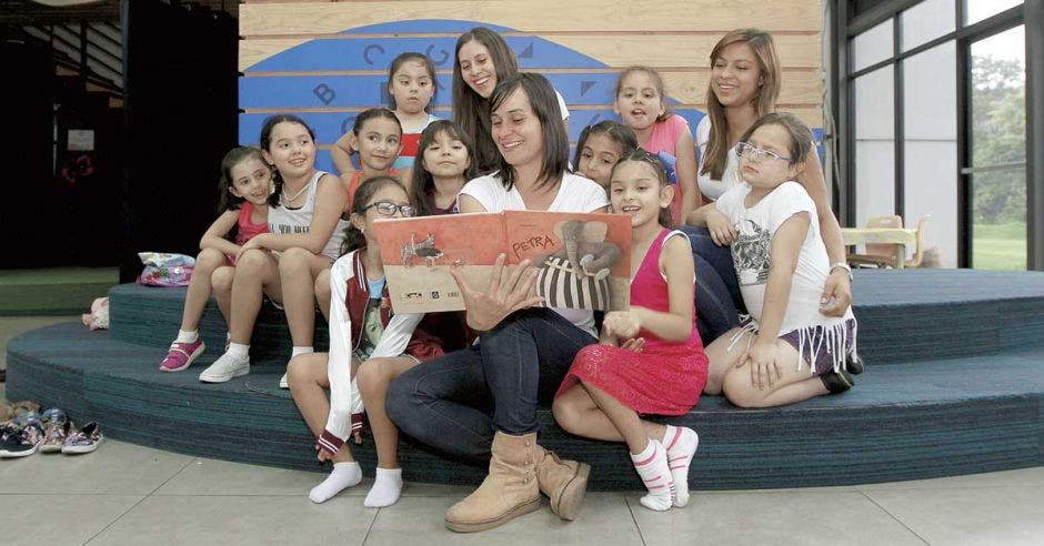 Ana Laura Araya (detrás a la izquierda) y Adriana Gómez (al frente a la derecha) son las confundadoras de Soy Niña. Gaby Quirós (centro, leyendo el libro) es la psicóloga y facilitadora de los clubes. Las acompañan las niñas de uno de los clubes.