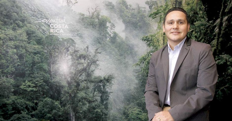 Alberto López, gerente general del ICT, posa sobre un póster de árboles y neblina.