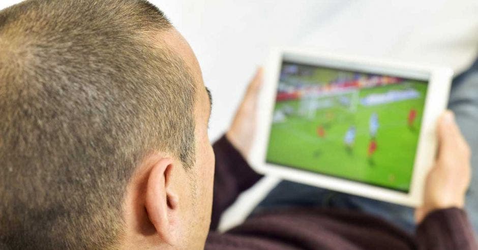 Un hombre mira un partido en streaming con su tablet.