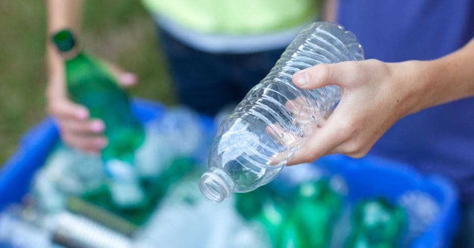 Una mano de hombre sostiene una botella de plástico