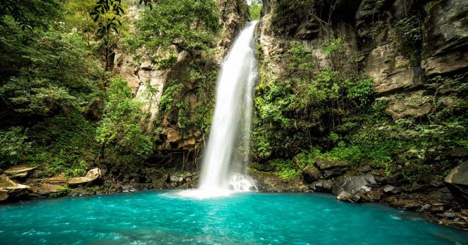 Una cascada cae sobre un río color celeste