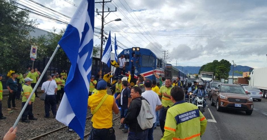 Trabajadores del sector público evitan el paso del tren en San José, al colocarse sobre las vías.