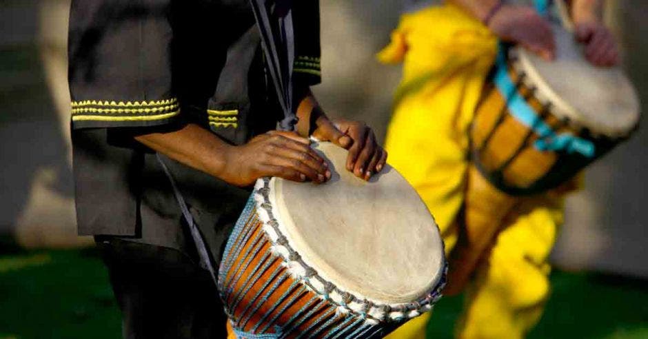 Dos afrodescendientes tocando  tambor tipo bongo