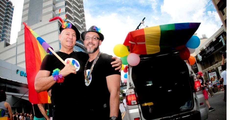 Dos hombres homosexuales posan con banderas y otra parafernalia alusiva al orgullo gay