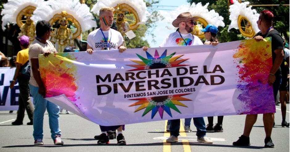 Cuatro marchantes sostienen un cartel que dice "marcha de la diversidad pintemos San José de colores.