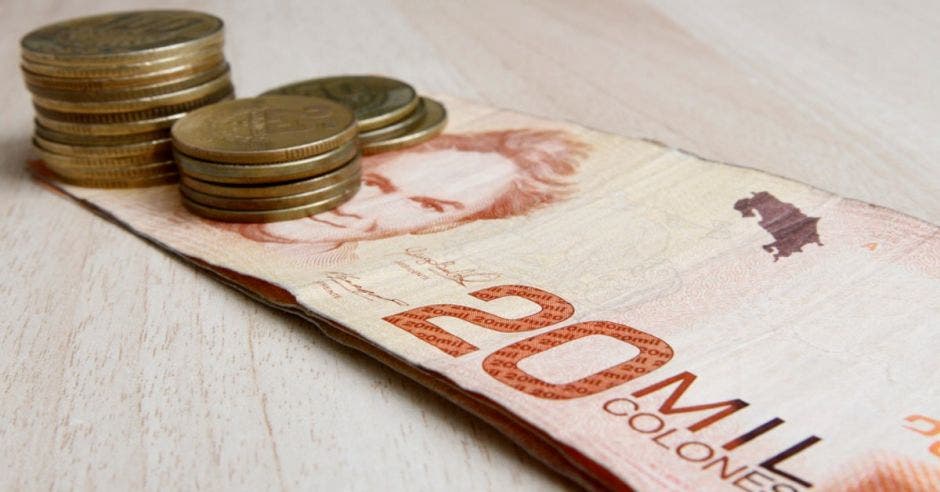 billete de 20 mil colones con monedas de cien colones