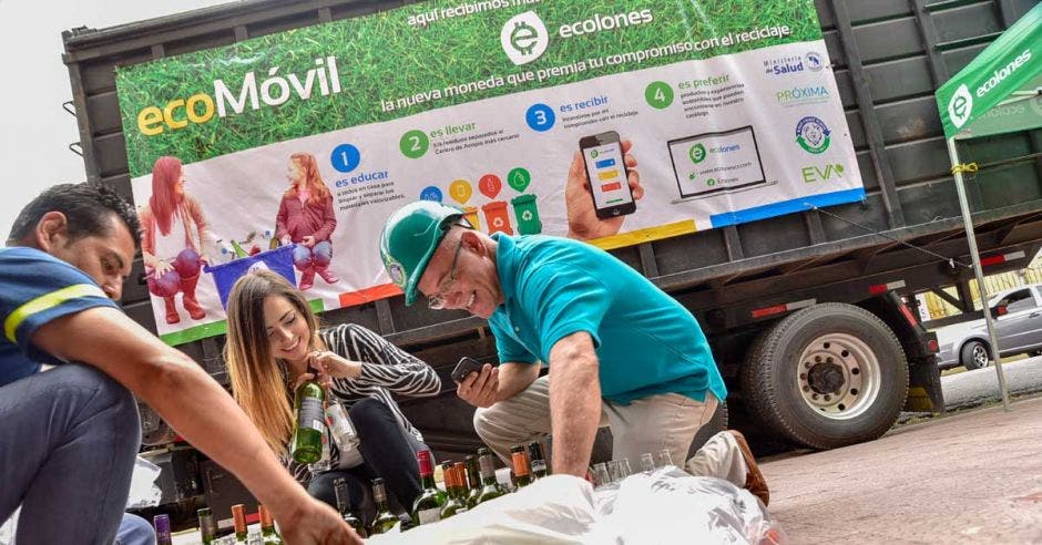 Un voluntario de ecolones recoge el material reciclado junto a dos clientes.