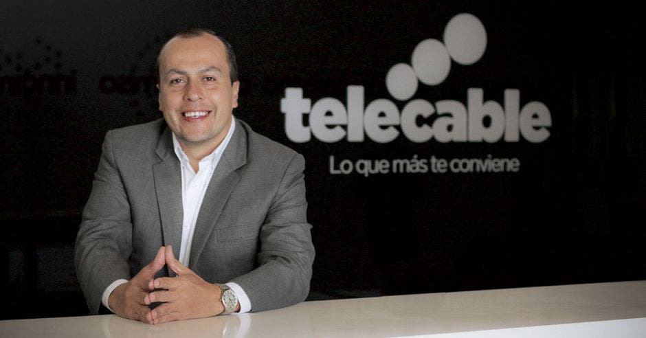 Rónald Jiménez, de Telecable, posa sonriente junto a un letrero de la empresa.