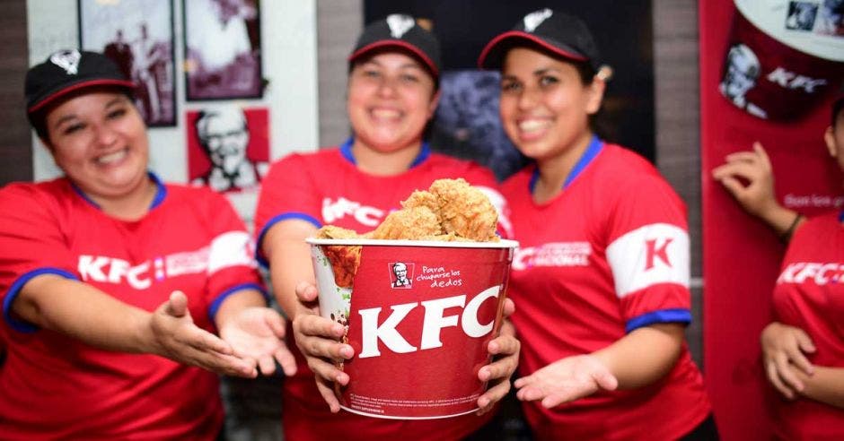 Tres empleadas de KFC sostienen una cubeta de pollo