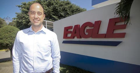 Arturo Rosabal posando junto a logo de la empresa.