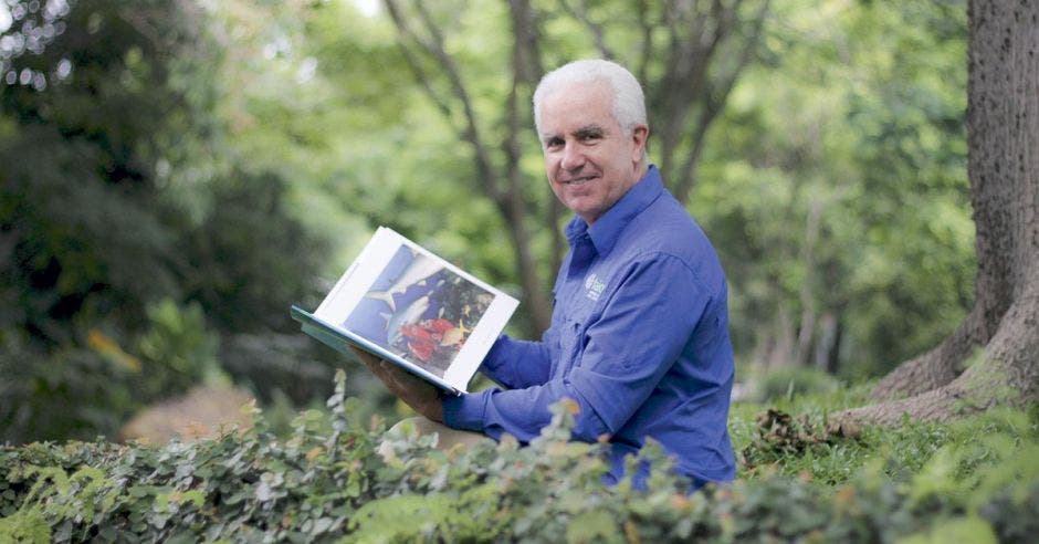 Carlos Uribe posa en un jardín con un libro de tiburones