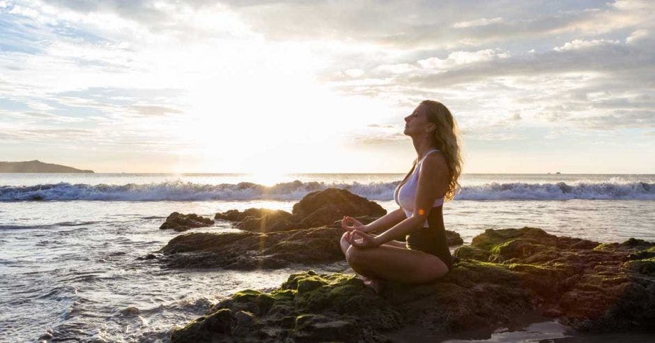 mujer practicando yoga en una playa tica