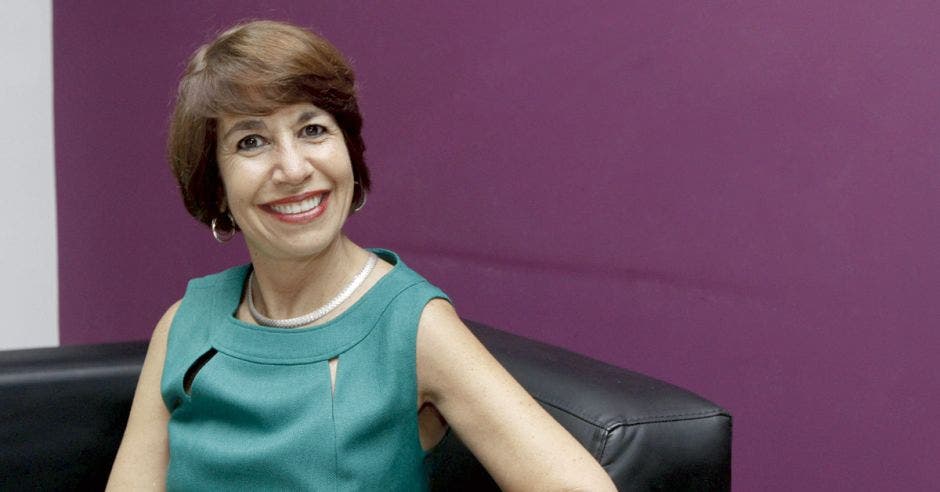 María Laura Arias posa en un sillón sobre una pared púpura