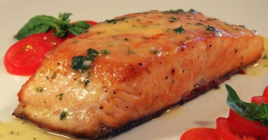 El salmón en salsa piccata con rodajas de tomate a los lados