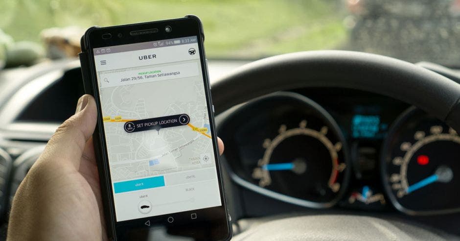 Un chofer sostiene el celular con Uber abierto