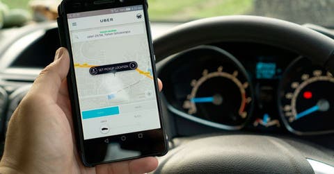 Un carro, un volante y la aplicación de Uber abierta en el celular