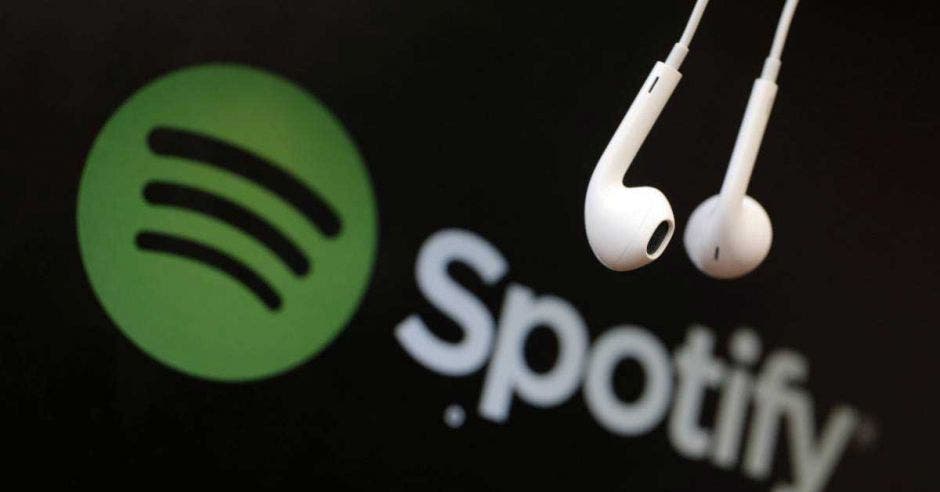 Dos audífonos cuelgan frente al logo de Spotify