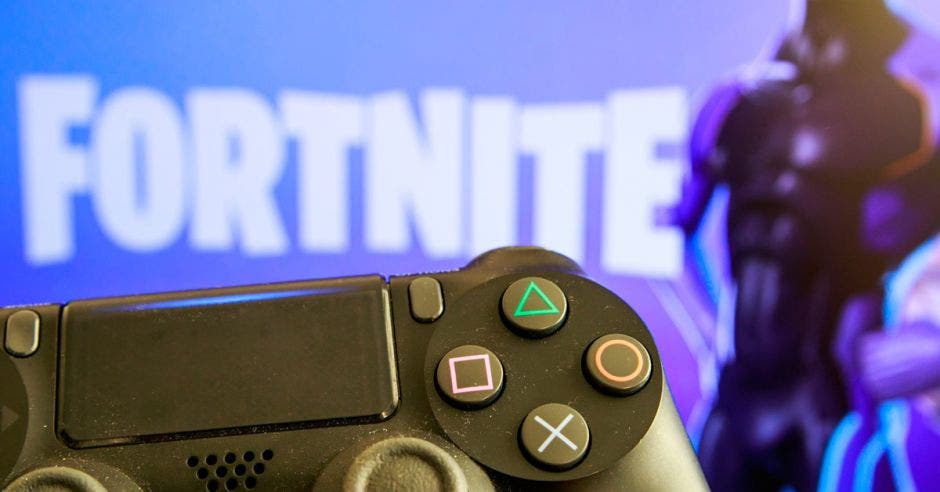 Un control de PS4 frente al logo de Fortnite