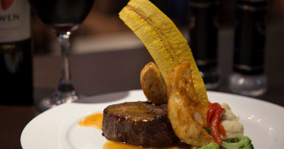 Lomito en un plato acompañado unos plátanos y brócoli