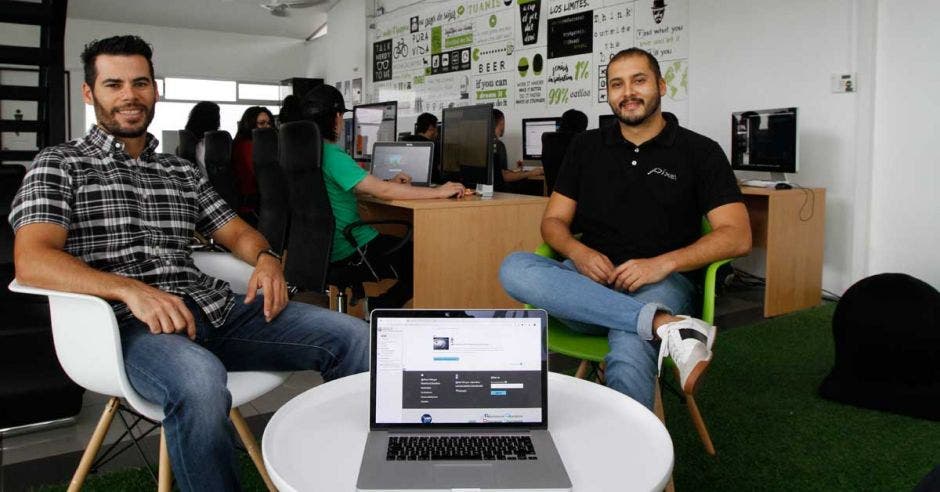 Luis Fernández y Joel Tinoco sentados en su oficina, frente a una computadora