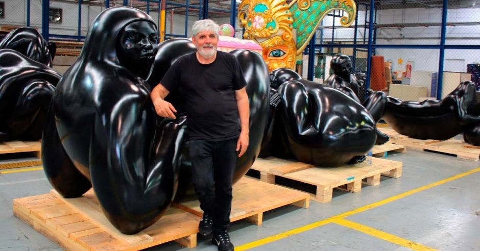 El artista apoyado en una de las esculturas de color negro