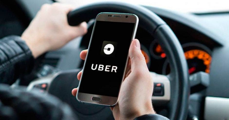 Un conductor de revisando el celular y sale el icono de uber en la plantalla del teléfono