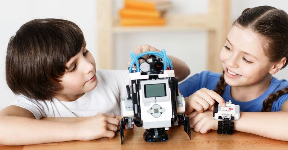 Un niño y una niña jugando con un robot.