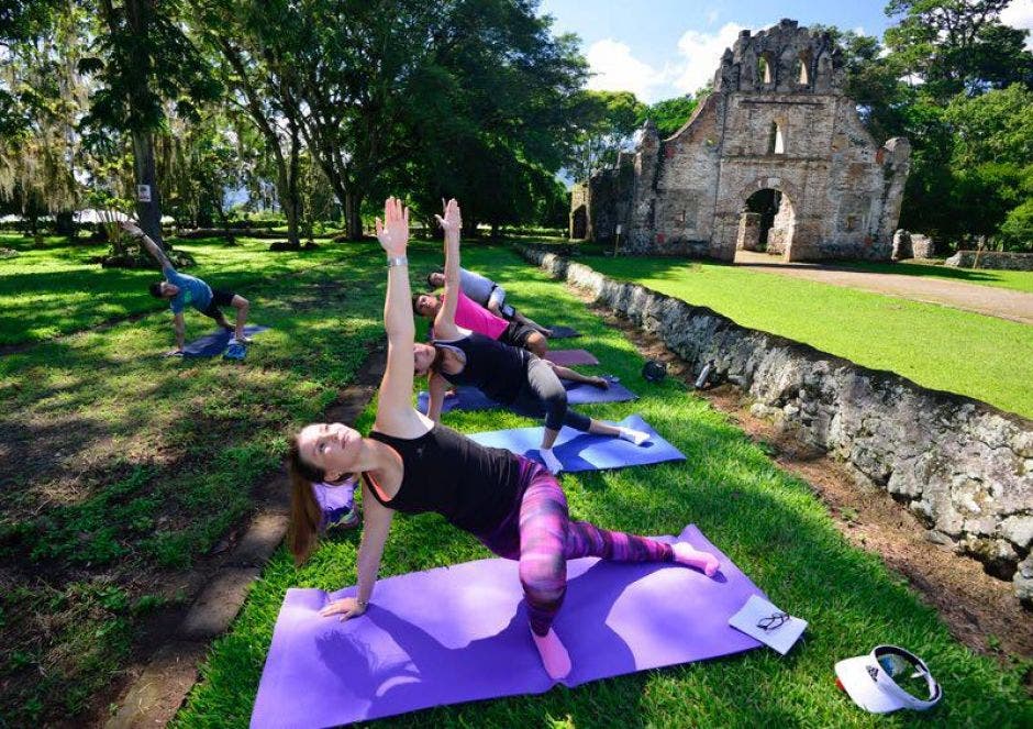 personas practicando yoga, de fondo ruinas de la iglesia colonial de Ujarrás.