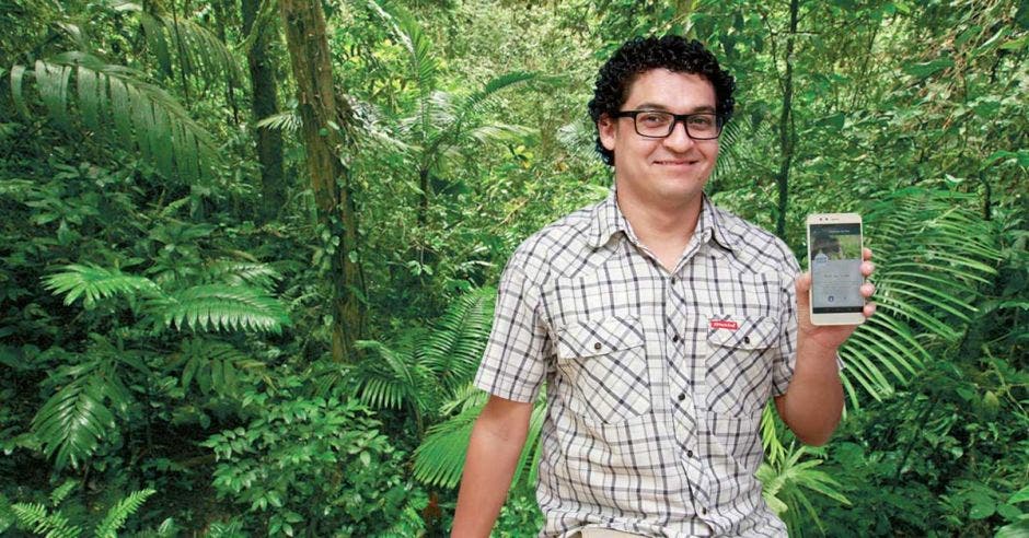 José Pablo Marín posa con un celular frente a una computadora