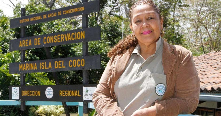 Una mujer posa junto a un letrero de parque nacional