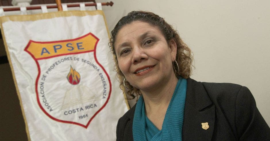 Mélida Cedeño posa para la cámara, al fondo se ve una bandera de la organización APSE.