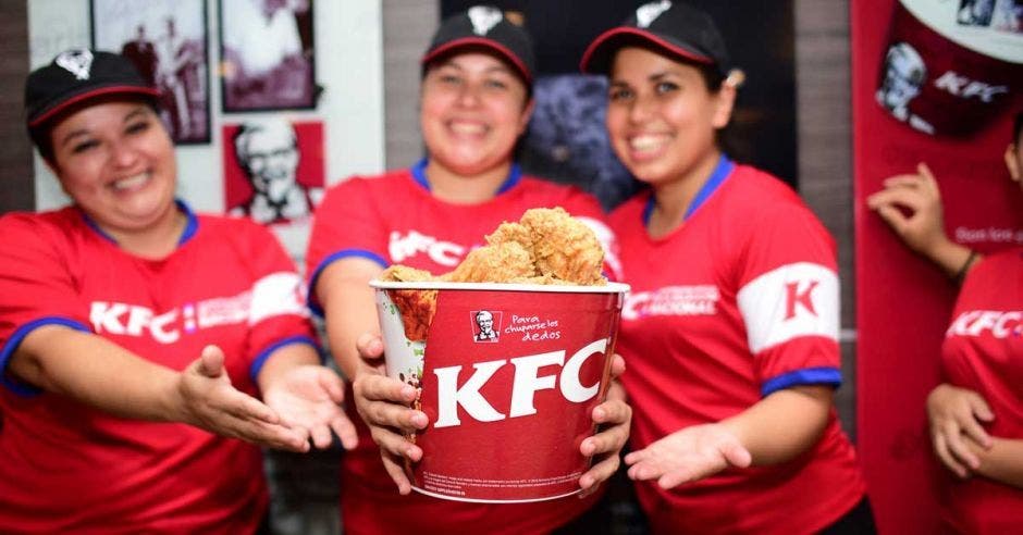 personal de KFC sosteniendo un tarro con pollo