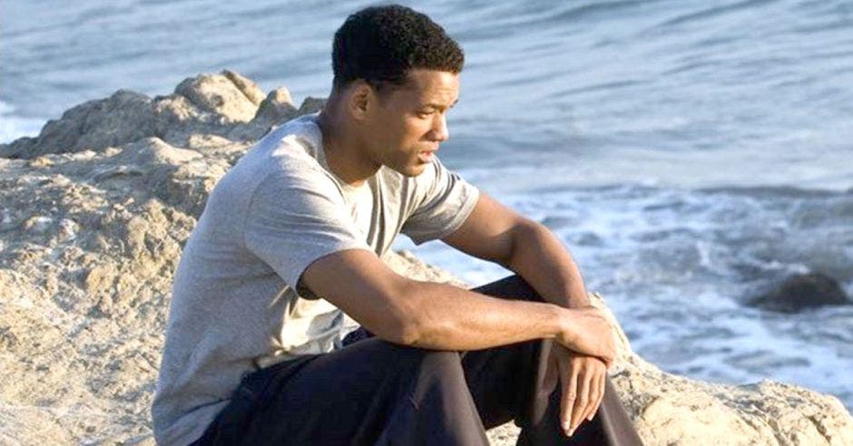 hombre sentado en un roca frente al mar pensativo