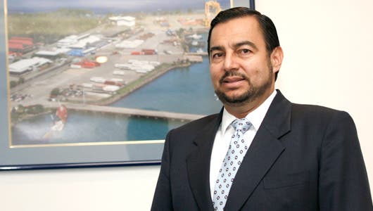 Francisco Jimenez expresidente de Japdeva con traje entero con un cuadro del puerto de Moín atrás