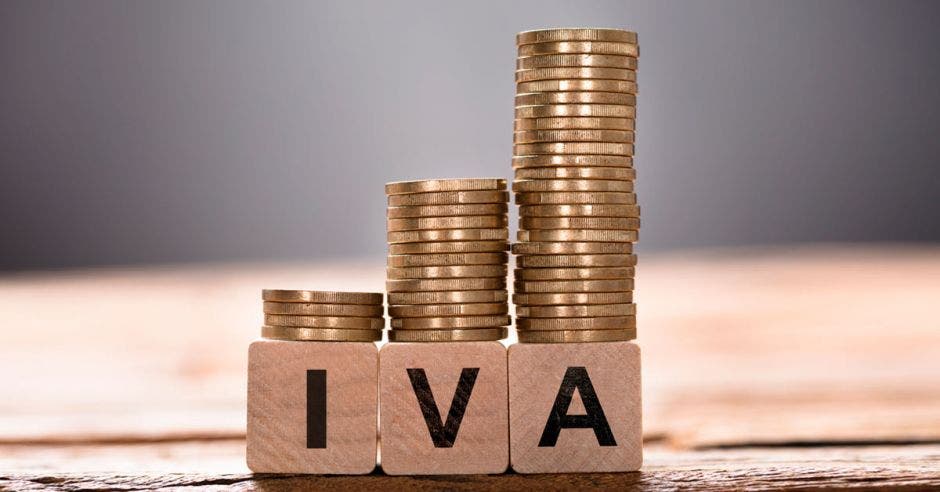 Foto de unas monedas apiladas y unas letras que dicen IVA