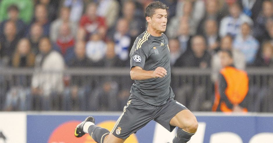 Jugador de futbol corriendo por la cancha con uniforme gris