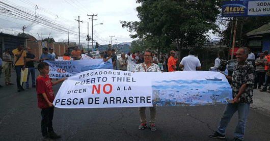 Un grupo de manifestantes sostienen una pancarta que dice "No a la pesca de arrastre"