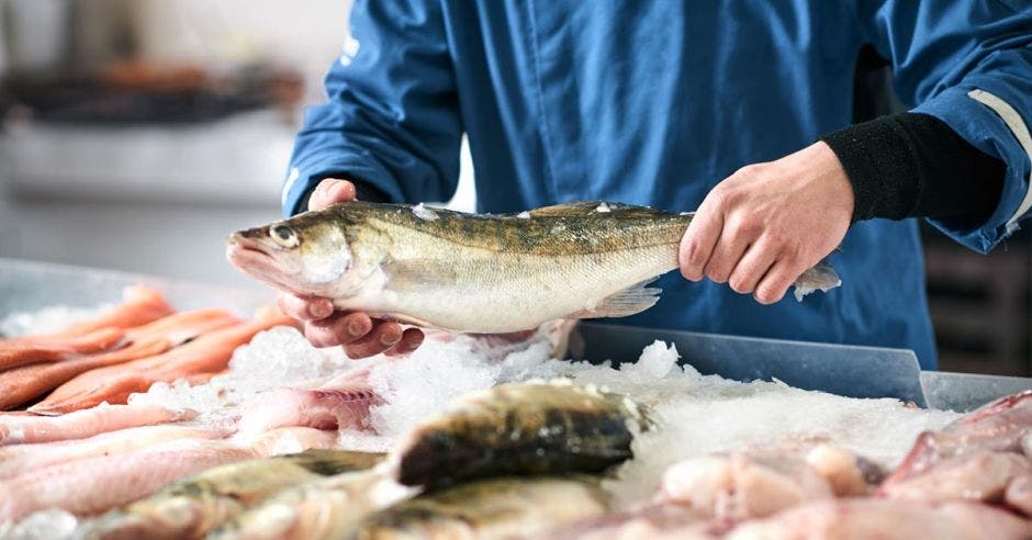 Un dependiente manipula un pescado en el mostrador