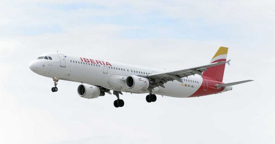 avión en el aire, blanco y la cola roja con amarillo