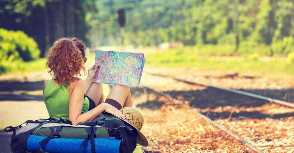 mujer con una maleta y un mapa esperando el tren