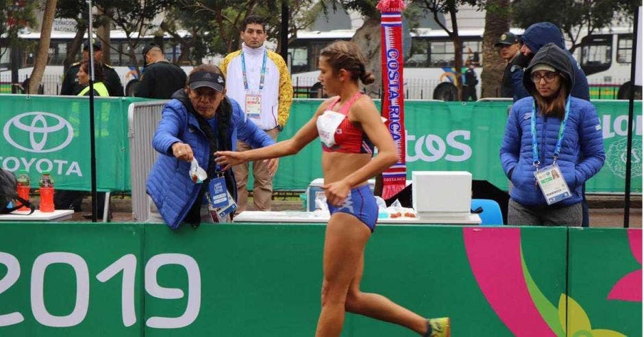 mamá ayuda a hija a darle agua mientras corre