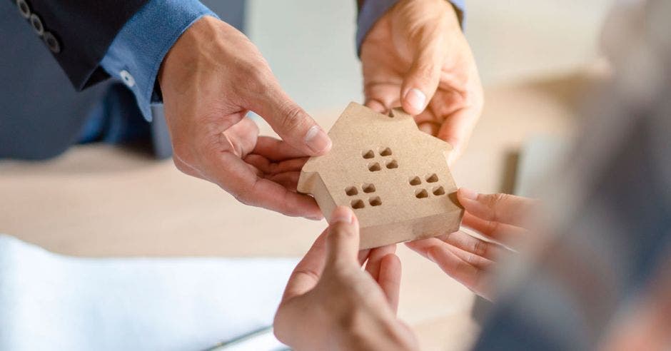 Manos de hombre y mujer sosteniendo una vivienda pequeña.