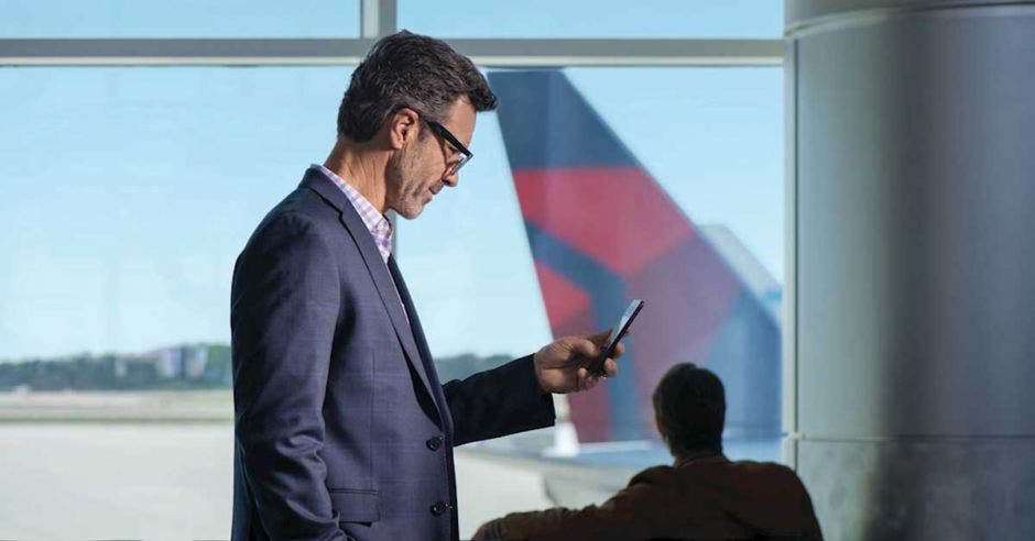 persona viendo el celular, está en el aeropuerto