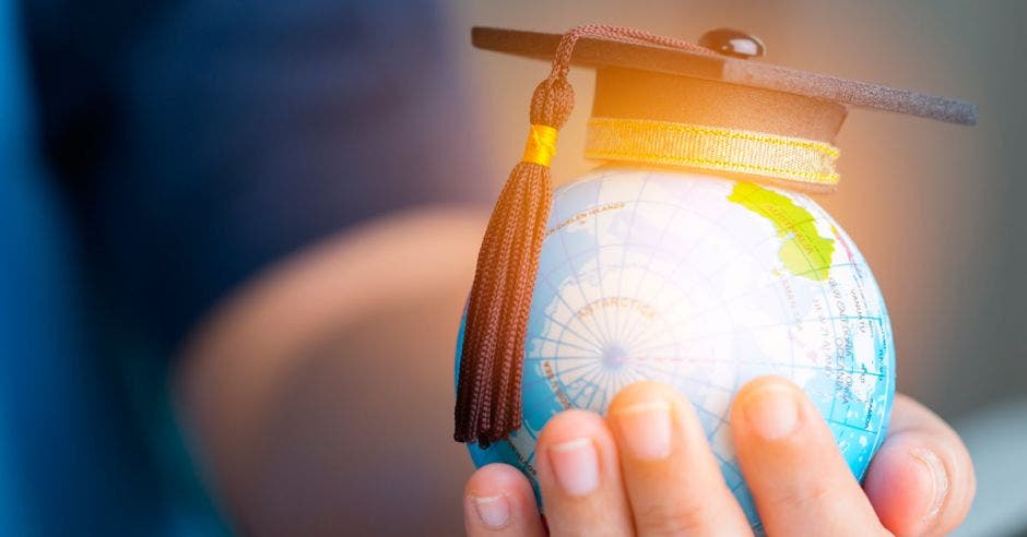 Una mano sosteniendo un globo terráqueo y un birrete