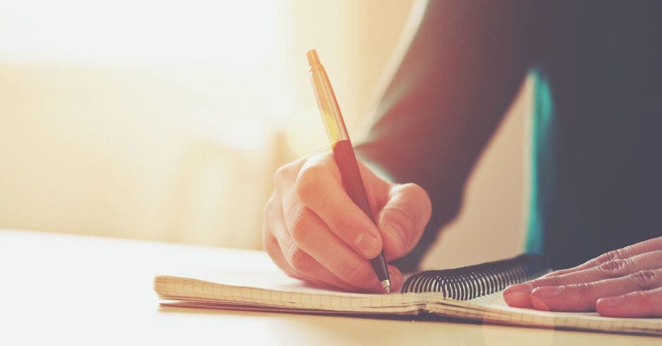 Una persona escribiendo en un cuaderno