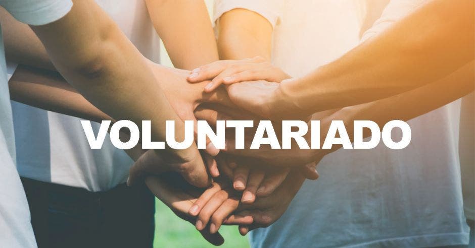 Varias personas uniendo las manos con la palabra voluntariado