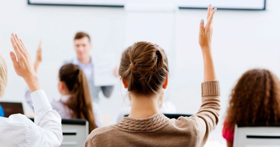 Jóvenes estudiantes levantando la mano en una clase