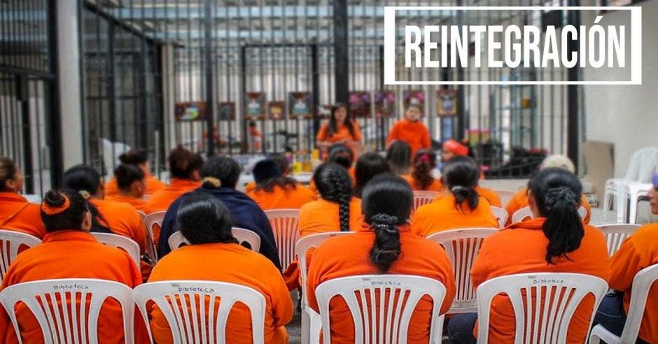 Un grupo de mujeres privadas de libertad, recibiendo una charla afuera de sus celdas