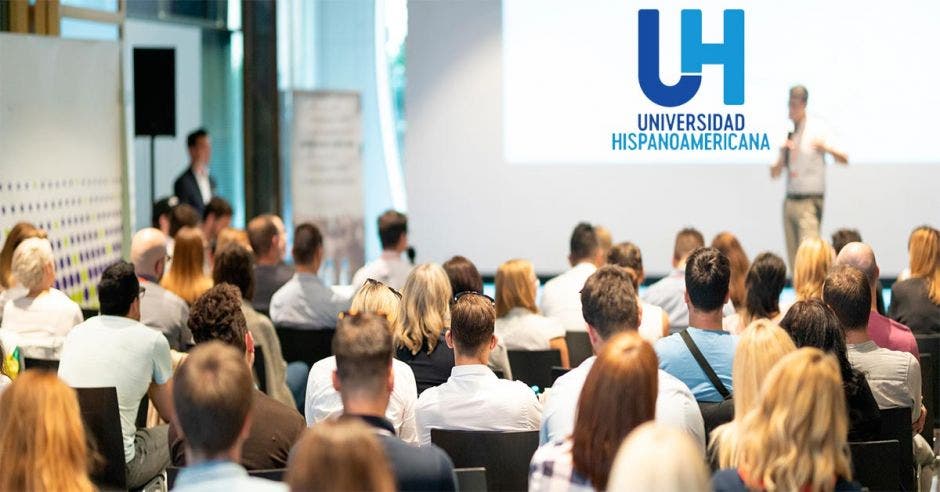 Una sala de conferencias con un logo de la Universidad Hispanoamericana