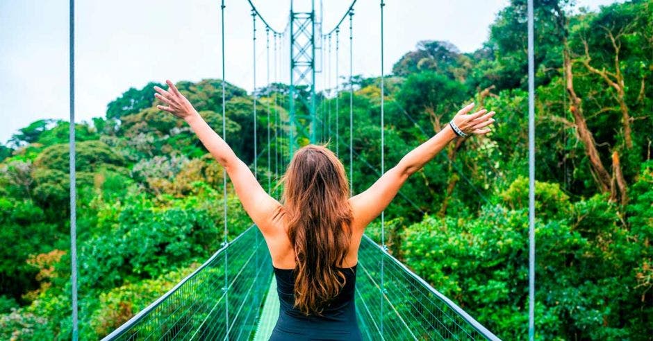 mujer en puente colgante en medio del bosque